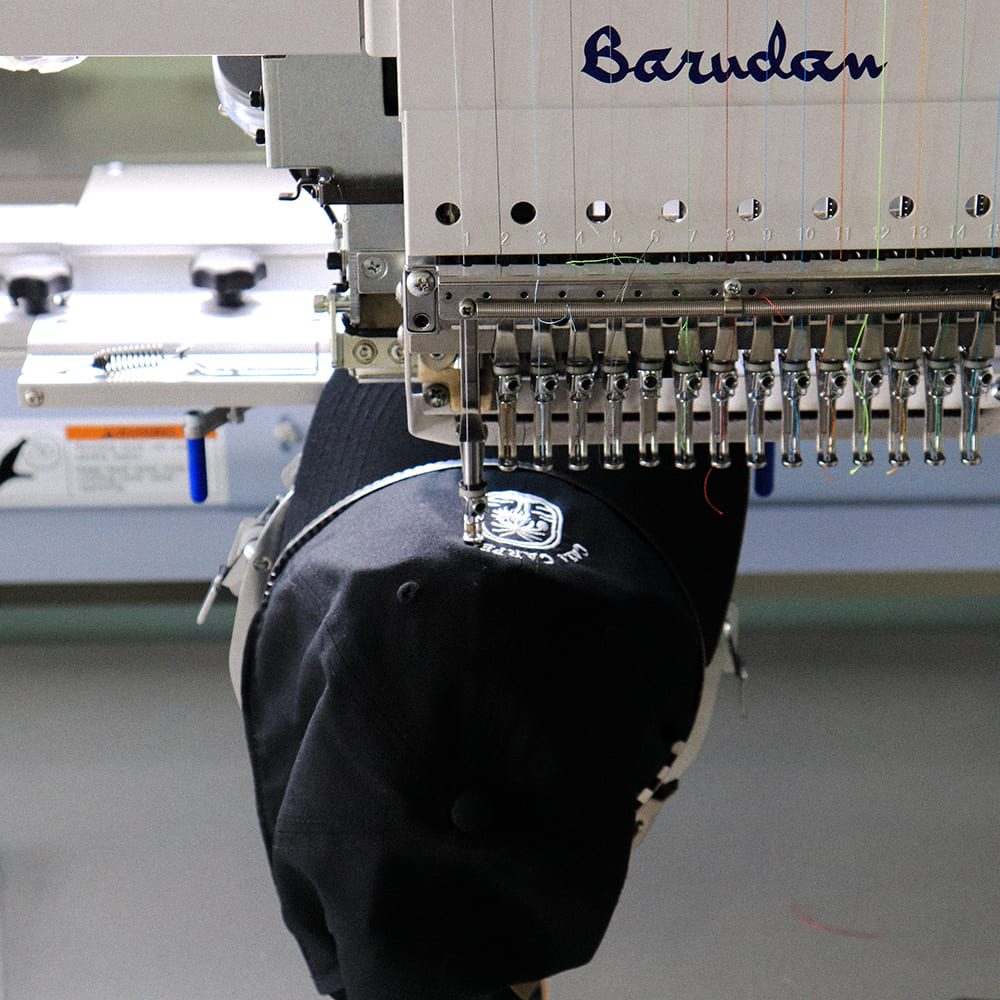 Embroidery – Cap being processed in embroidery machine Embroidery - Cap being processed in embroidery machine